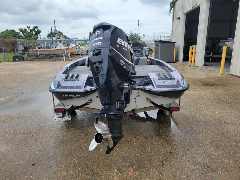 Slide: The Image of 1994 Javelin 379 boat with Evinrude 150 motor, parked outside a garage. - 4