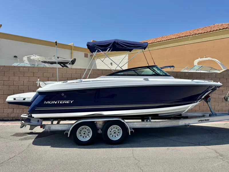 The Image of 2016 Monterey 244FS boat on trailer, blue hull, parked outdoors. - 0