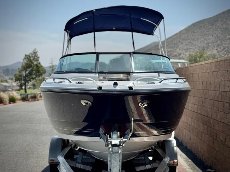 Slide: The Image of 2016 Monterey 244FS boat on trailer, parked outdoors with mountains in background. - 2