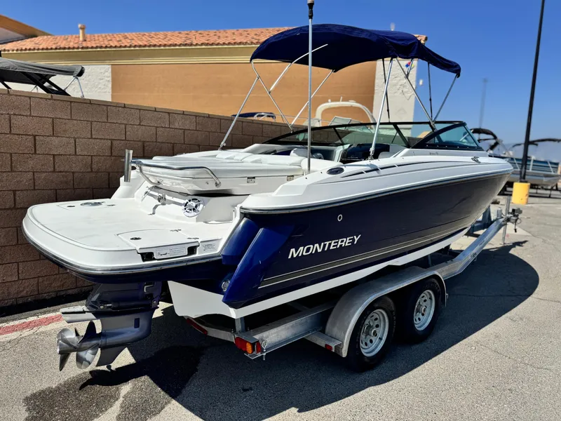Slide: The Image of 2016 Monterey 244FS boat on trailer, blue and white, parked outdoors. - 5