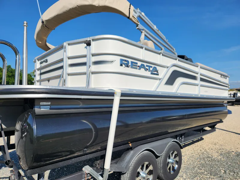 Slide: The Image of 2018 Ranger Reata 220C pontoon boat on a trailer under a clear blue sky. - 3