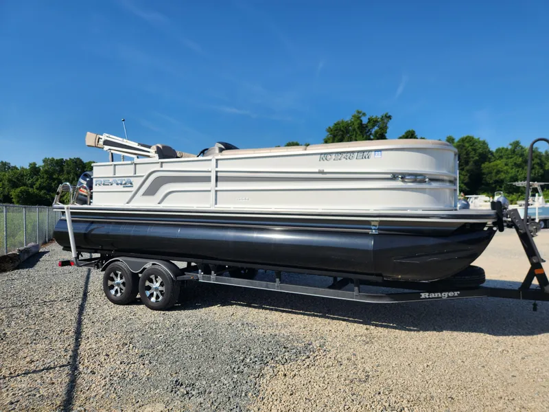 Slide: The Image of 2018 Ranger Reata 220C pontoon boat on a trailer in a gravel lot. - 5