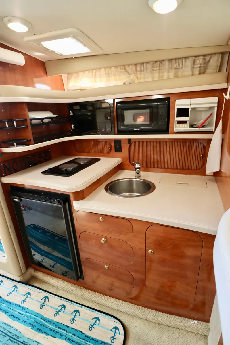 Slide: The Image of 2002 Rinker 342 Fiesta Vee boat interior kitchen with sink, stove, microwave, and storage. - 8