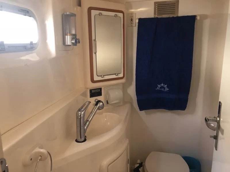 Slide: The Image of Compact bathroom in 2003 Leopard 47 yacht with sink, mirror, and blue towel. - 27