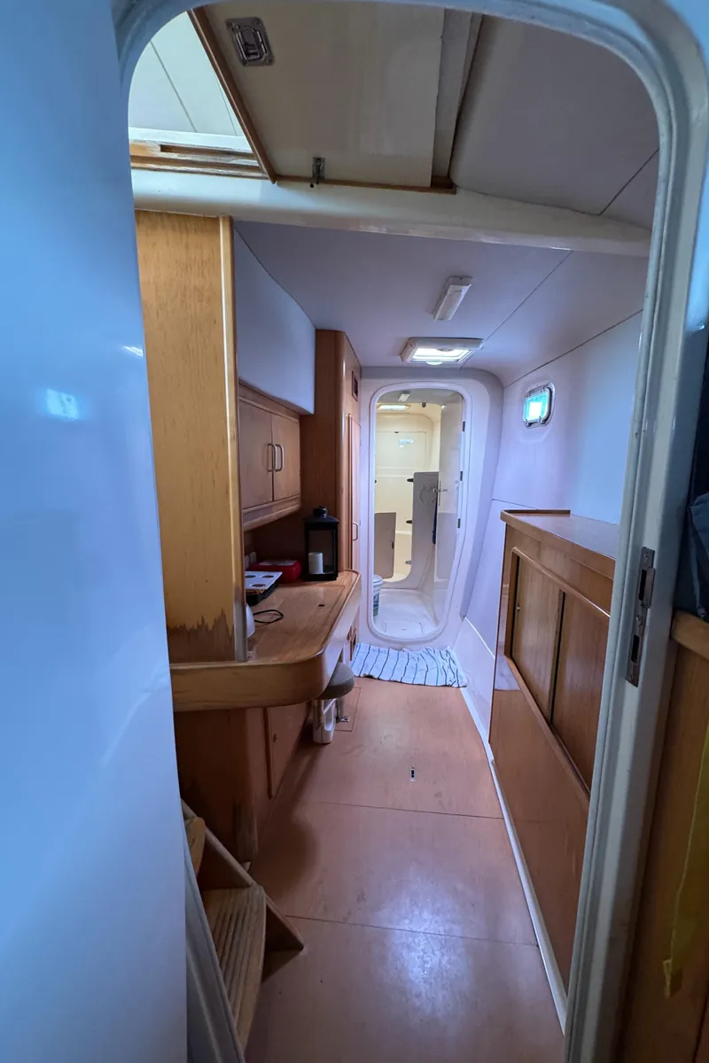 Slide: The Image of Interior of 2003 Leopard 47 yacht, featuring wooden cabinetry and a narrow passageway. - 34