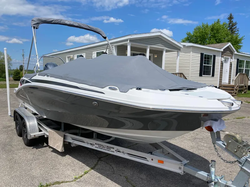 Slide: The Image of 2022 Hurricane SS 205 boat on trailer, covered, parked near houses under blue sky. - 19