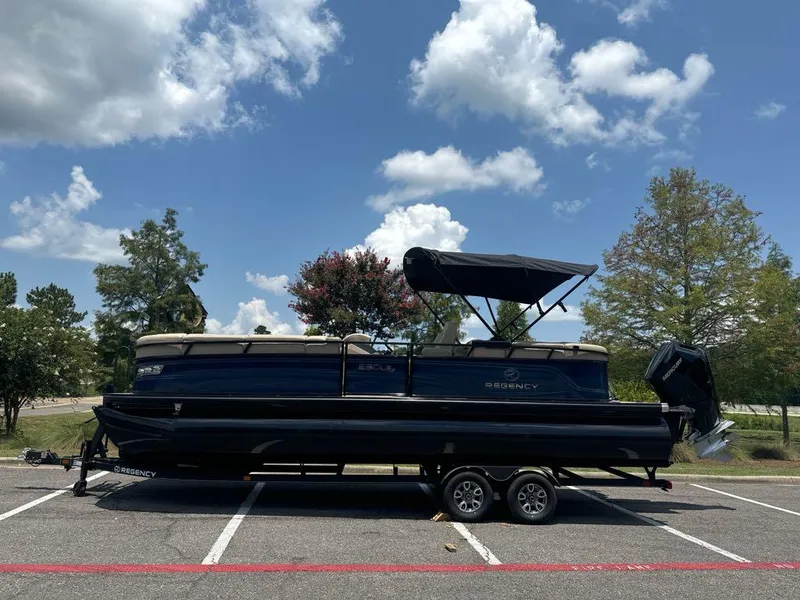 Slide: The Image of 2024 Regency 250 LE3 pontoon boat on trailer in parking lot. - 0