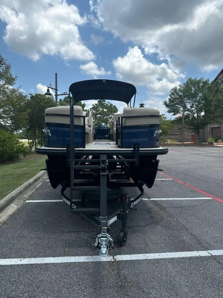 Slide: The Image of 2024 Regency 250 LE3 pontoon boat on a trailer in a parking lot. - 3