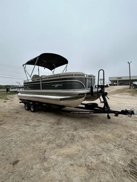 Slide: The Image of 2024 Sun Tracker Party Barge 20 DLX pontoon boat on trailer, outdoor display. - 2