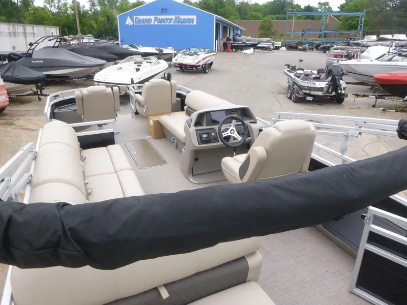 Slide: The Image of 2024 Sun Tracker Sportfish 24 XP3 pontoon boat at marina, featuring spacious seating and helm. - 14