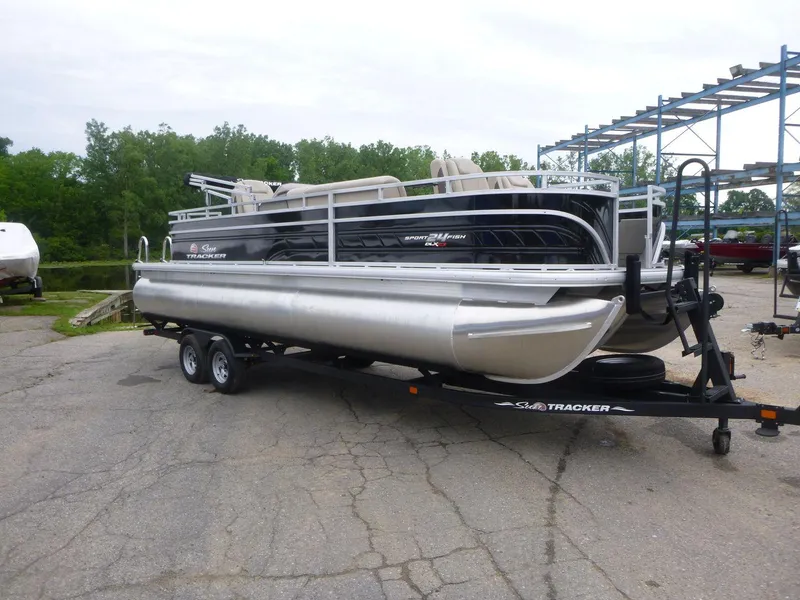 Slide: The Image of 2024 Sun Tracker Sportfish 24 XP3 pontoon boat on trailer, parked outdoors. - 3