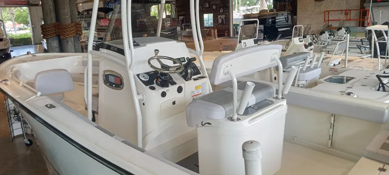 Slide: The Image of 2024 Mako 214 CC boat interior with steering console and seating in showroom. - 3