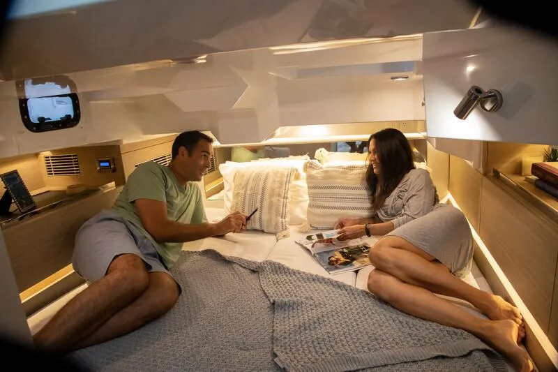 Slide: The Image of Couple relaxing in the cozy cabin of a 2024 Jeanneau Leader 10.5 CC boat. - 10