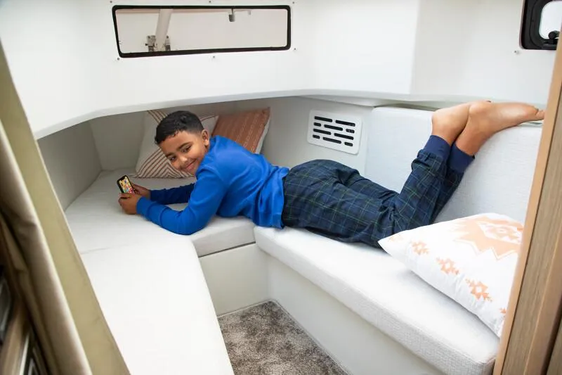 Slide: The Image of 2024 Jeanneau Leader 10.5 CC cabin interior with a child relaxing on the bed. - 9