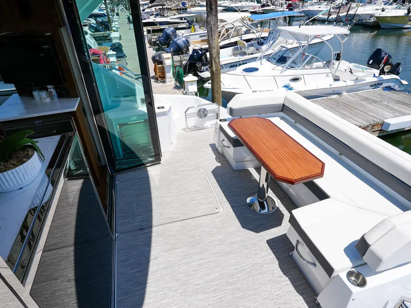 Slide: The Image of 2021 Cruisers Yachts 50 Cantius deck with seating and table, docked at marina. - 10