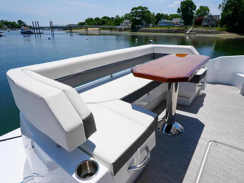 Slide: The Image of 2021 Cruisers Yachts 50 Cantius aft deck seating with table, overlooking serene waterfront. - 14
