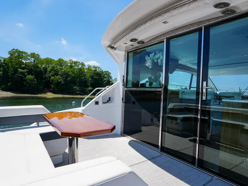 Slide: The Image of 2021 Cruisers Yachts 50 Cantius aft deck with seating and table, overlooking serene waters. - 16