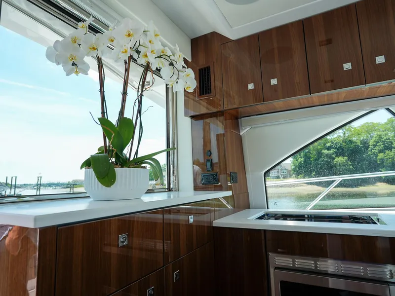Slide: The Image of 2021 Cruisers Yachts 50 Cantius kitchen with wooden cabinets and a potted orchid. - 24