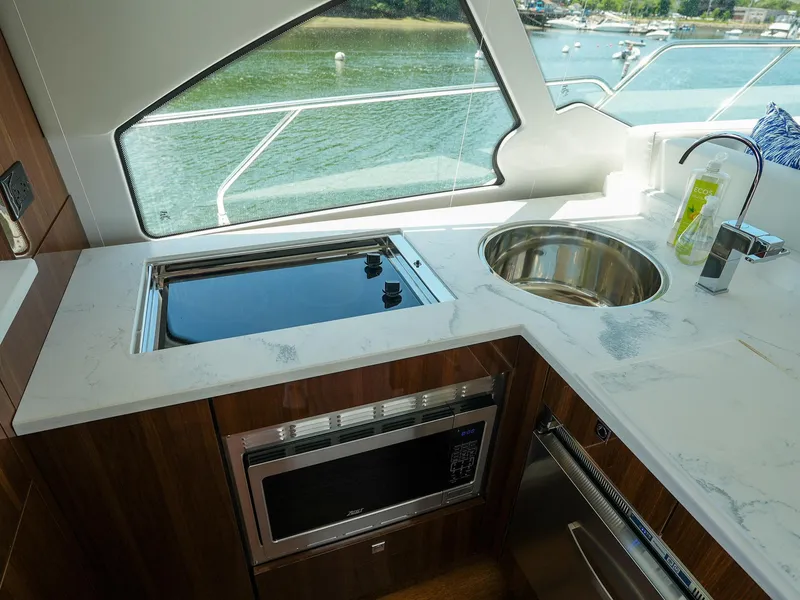 Slide: The Image of Modern kitchen area in 2021 Cruisers Yachts 50 Cantius with sink, stove, and microwave. - 25