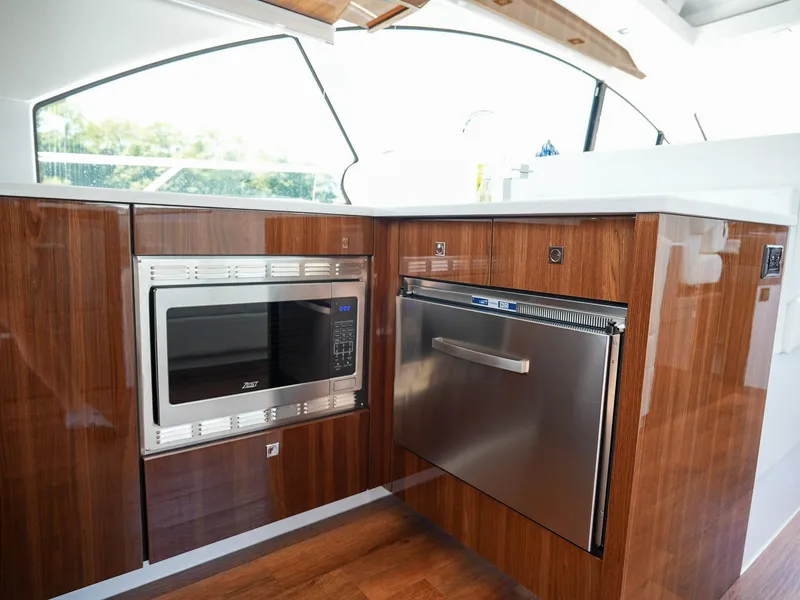 Slide: The Image of Modern kitchen area in 2021 Cruisers Yachts 50 Cantius with microwave and stainless steel appliances. - 27