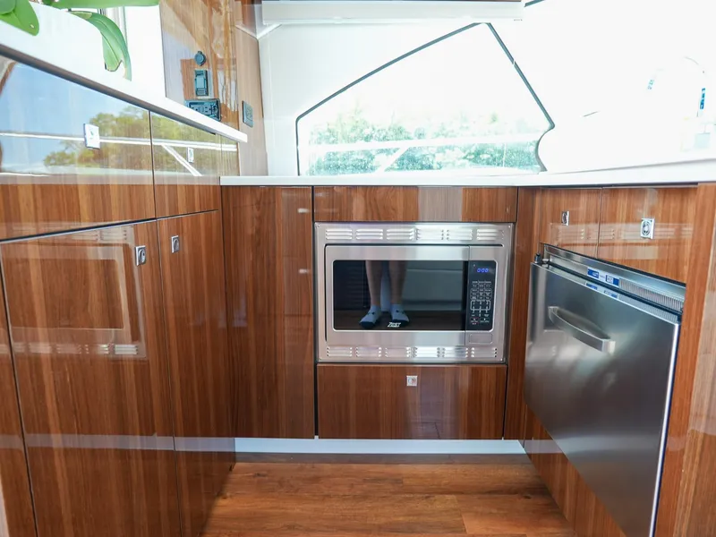 Slide: The Image of Modern kitchen in 2021 Cruisers Yachts 50 Cantius with wood cabinetry and stainless steel appliances. - 28