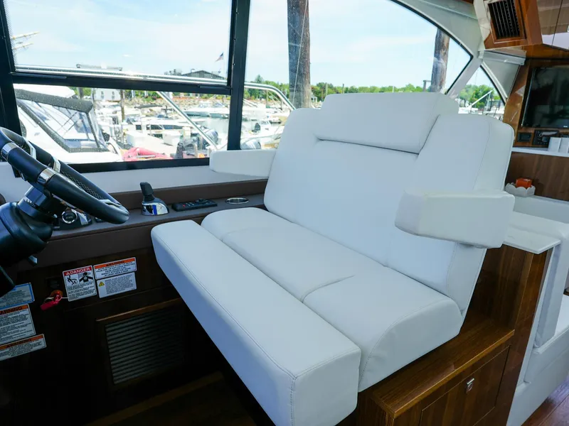 Slide: The Image of Captain's seat and helm of 2021 Cruisers Yachts 50 Cantius, featuring white leather upholstery. - 33