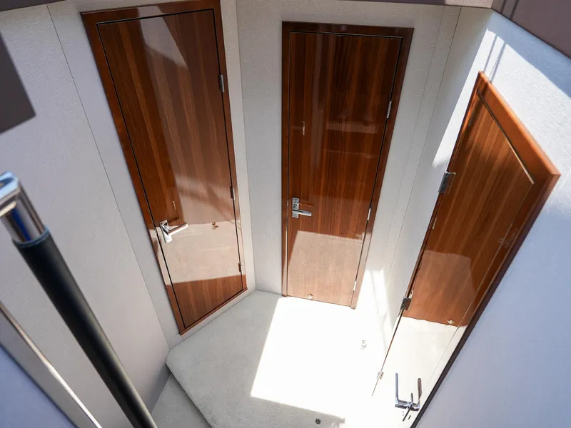 Slide: The Image of Interior hallway of 2021 Cruisers Yachts 50 Cantius with three wooden doors. - 41