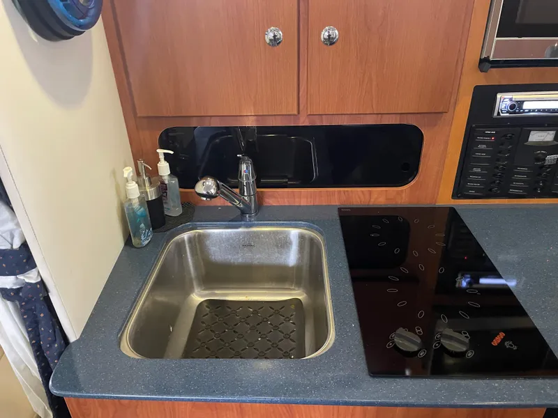 Slide: The Image of 2008 Bayliner 340 kitchen sink and stove area with wooden cabinets. - 26