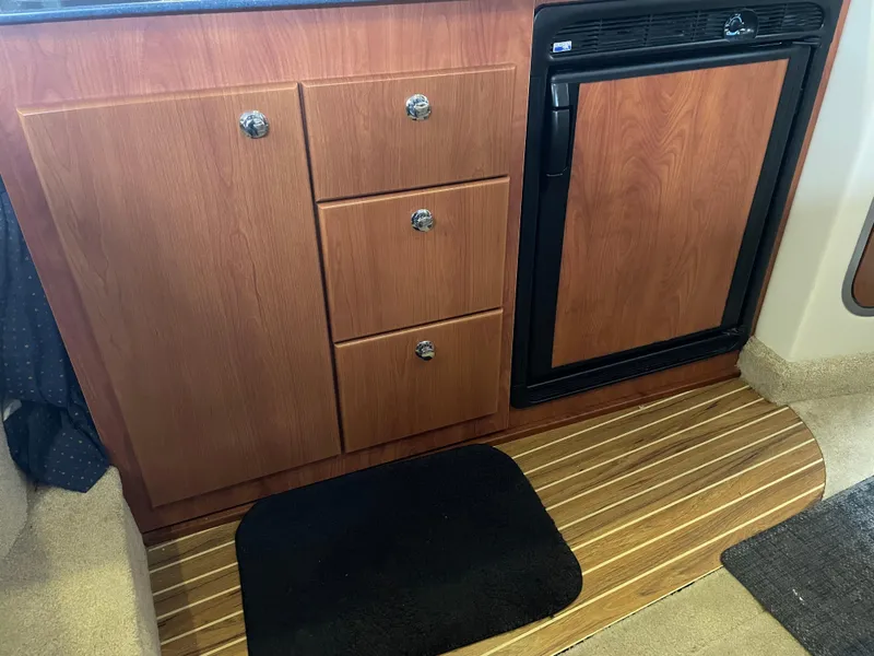 Slide: The Image of 2008 Bayliner 340 galley with wooden cabinets and mini-fridge. - 27