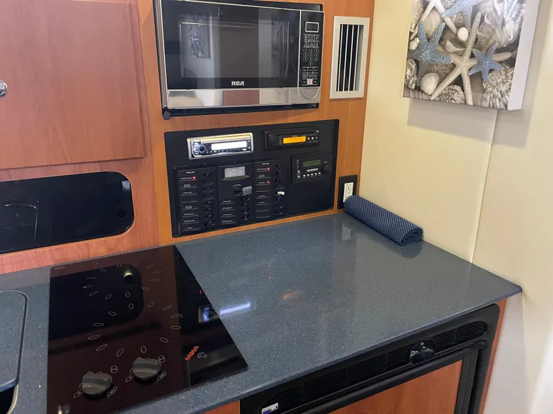 Slide: The Image of 2008 Bayliner 340 yacht kitchen with microwave, stove, and control panel. - 28