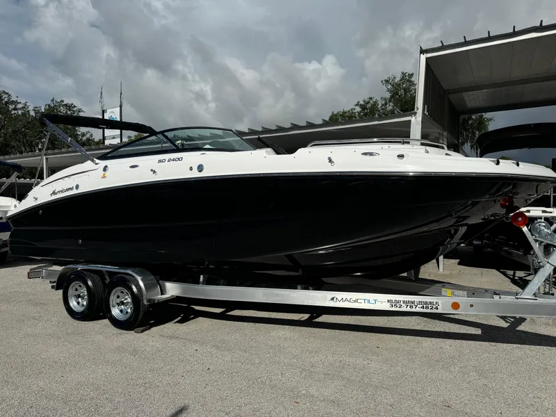 The Image of 2024 Hurricane SunDeck 2400 OB boat on a trailer in a marina. - 1