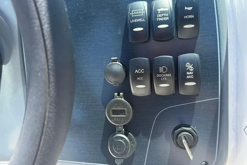 Slide: The Image of Control panel of 2026 Hurricane SunDeck 2400 OB boat with various switches and ignition key. - 18
