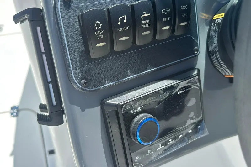 Slide: The Image of Control panel of 2026 Hurricane SunDeck 2400 OB boat with stereo and accessory switches. - 19