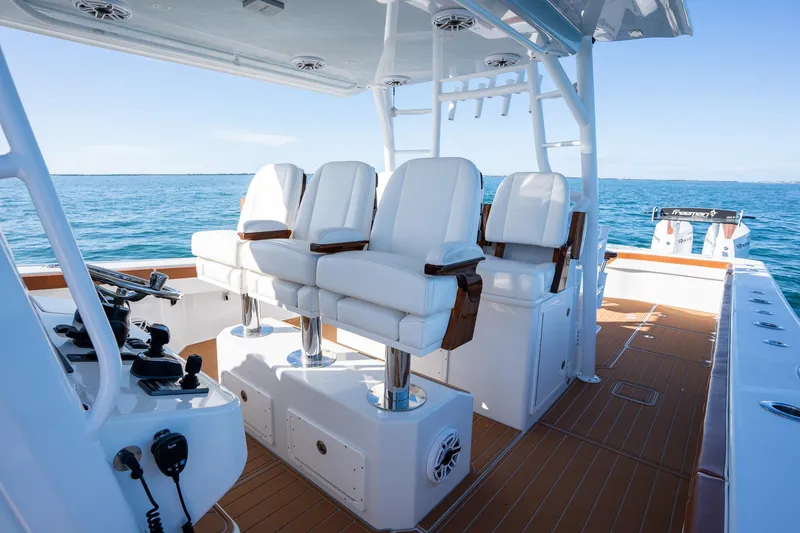 Slide: The Image of Freeman 47 boat interior, 2022 model, featuring white captain chairs and teak flooring. - 17