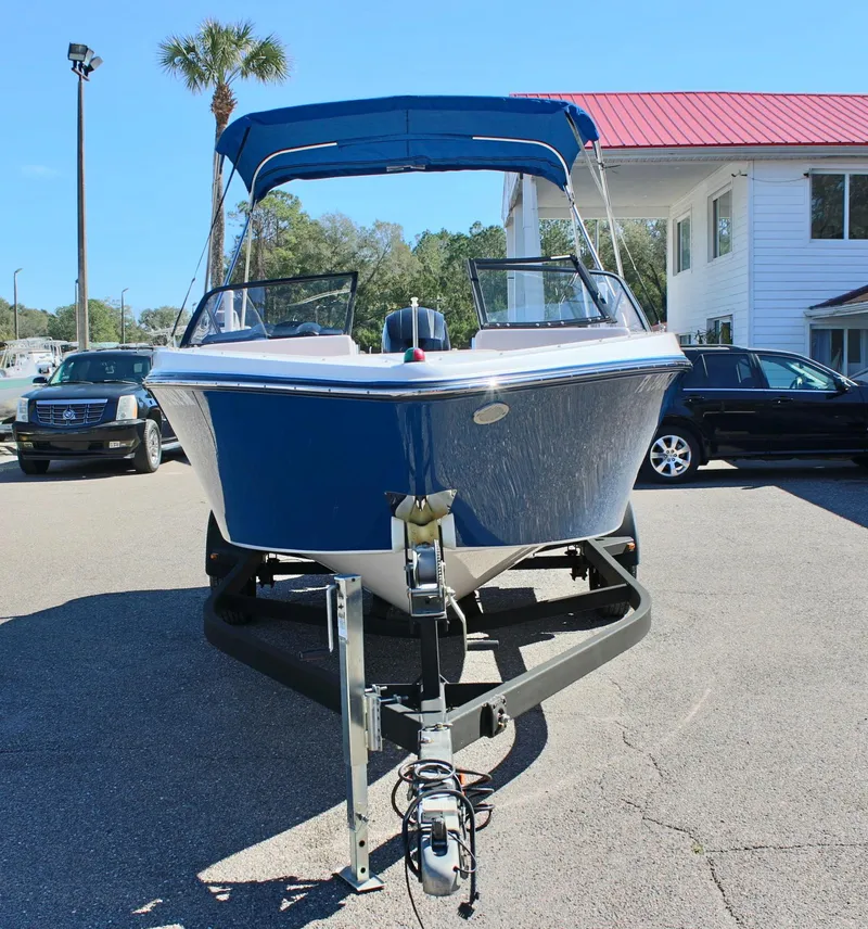 Slide: The Image of 2018 Glastron GT200 boat on trailer, blue and white, parked outdoors. - 2