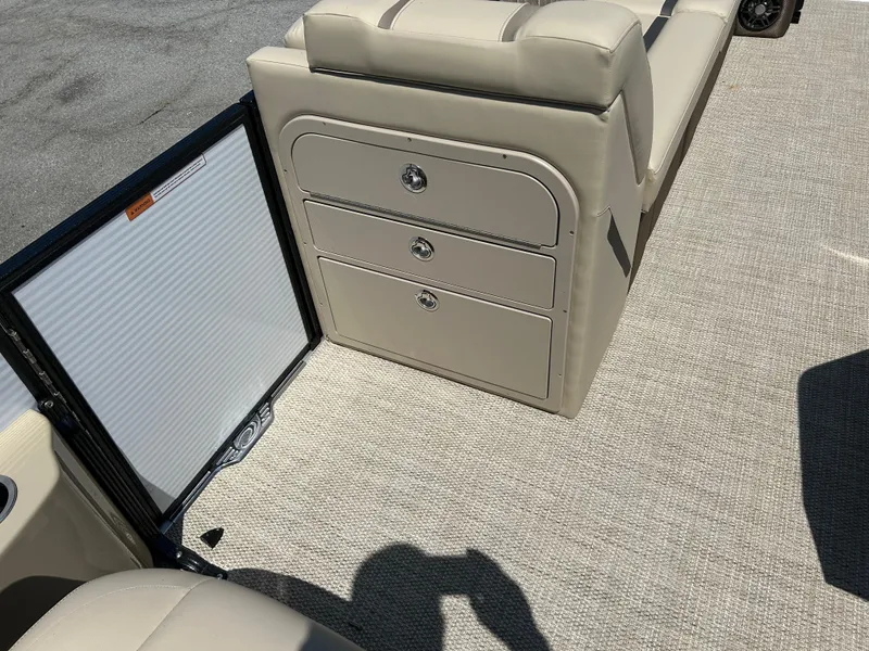 Slide: The Image of 2024 Crest Classic Platinum 240 SLC boat interior with beige seating and storage compartments. - 12