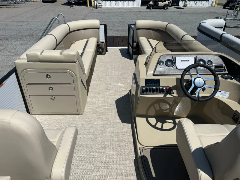 Slide: The Image of 2024 Crest Classic Platinum 240 SLC pontoon boat interior with beige seating and steering console. - 9