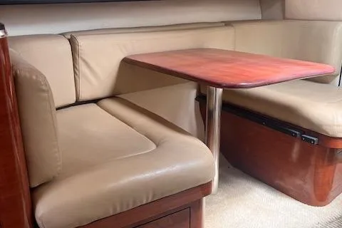 Slide: The Image of 2007 Sea Ray 290 Amberjack interior dining area with beige leather seating and wooden table. - 4