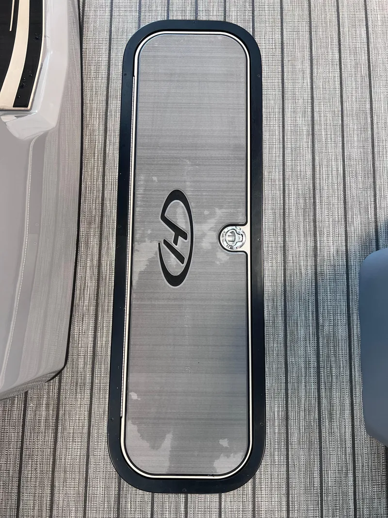 Slide: The Image of 2024 Harris Solstice 230 boat storage compartment with logo on textured flooring. - 17