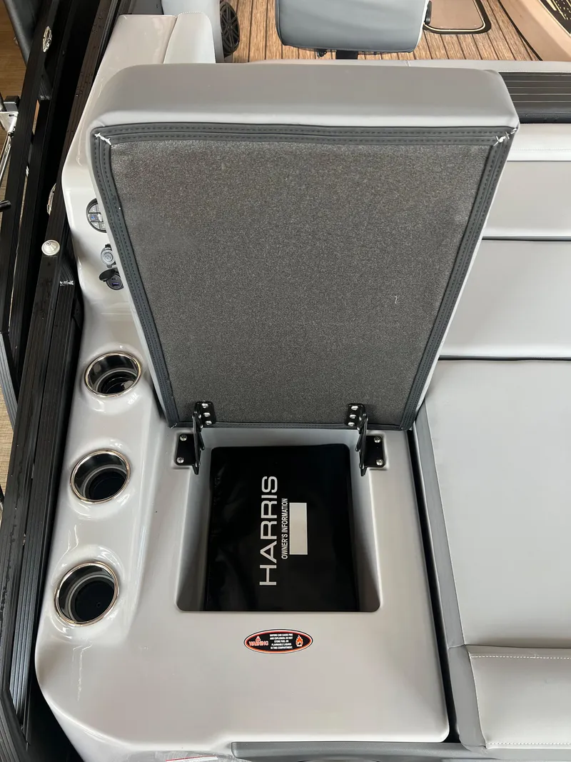 Slide: The Image of 2024 Harris Solstice 230 boat with open storage compartment and cup holders. - 24