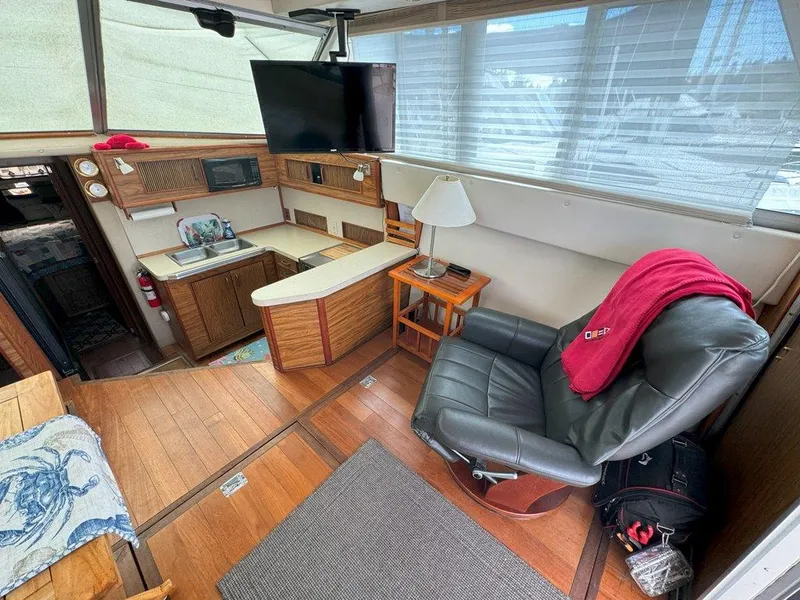 Slide: The Image of Interior of 1985 Sea Ray 390 Sedan Bridge with leather chair, TV, and kitchenette. - 12