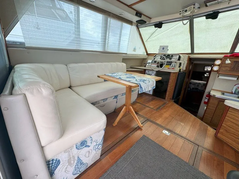 Slide: The Image of Interior of 1985 Sea Ray 390 Sedan Bridge with white leather seating and wooden table. - 13