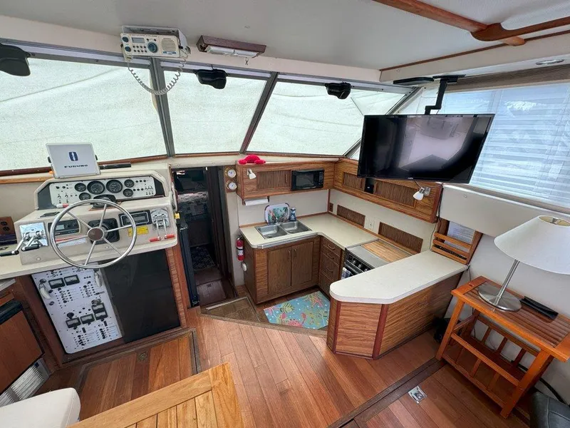 Slide: The Image of Interior of 1985 Sea Ray 390 Sedan Bridge with helm, kitchen, and TV. - 14