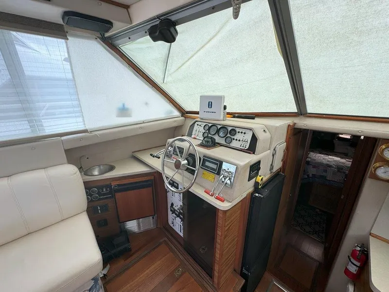 Slide: The Image of 1985 Sea Ray 390 Sedan Bridge helm with steering wheel, controls, and cabin entrance. - 15