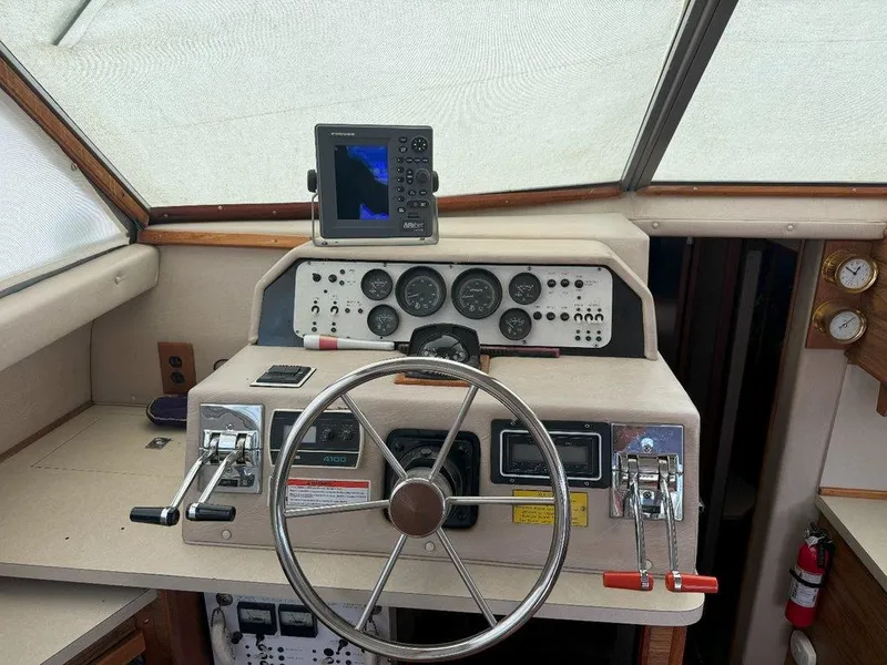Slide: The Image of 1985 Sea Ray 390 Sedan Bridge helm with steering wheel, gauges, and navigation equipment. - 16