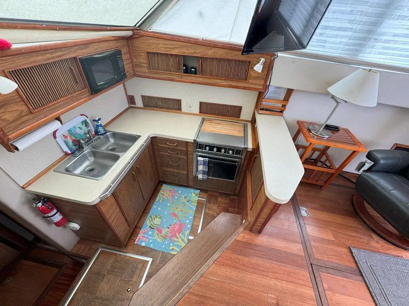 Slide: The Image of 1985 Sea Ray 390 Sedan Bridge kitchen with sink, stove, and microwave. - 17