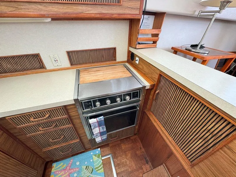 Slide: The Image of 1985 Sea Ray 390 Sedan Bridge kitchen with stove and wooden cabinetry. - 18