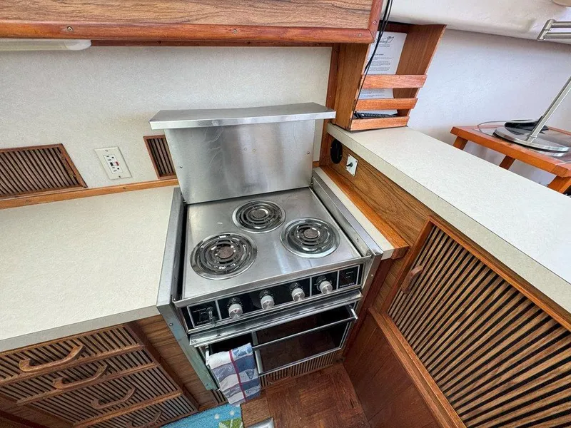 Slide: The Image of 1985 Sea Ray 390 Sedan Bridge kitchen with electric stove and wooden cabinetry. - 19