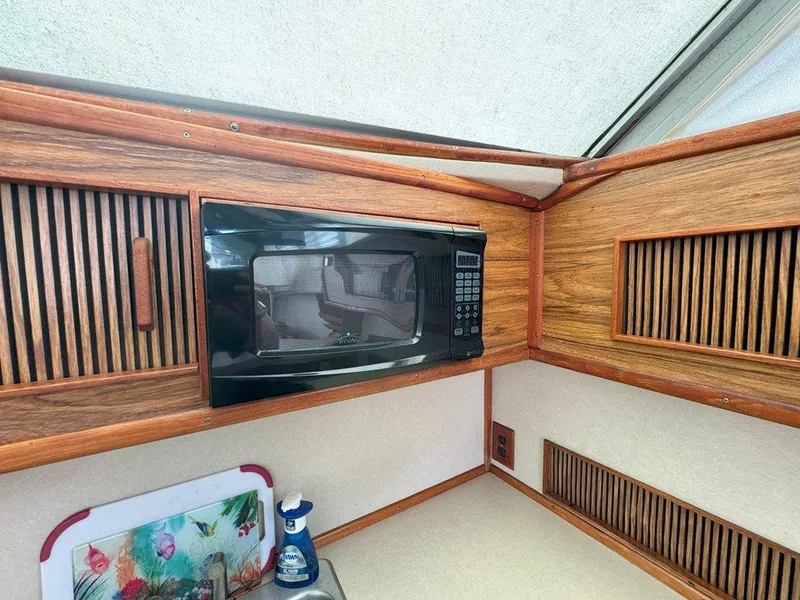 Slide: The Image of 1985 Sea Ray 390 Sedan Bridge kitchen with microwave and wooden cabinets. - 21