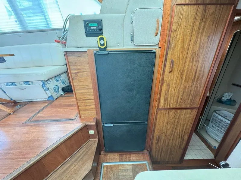 Slide: The Image of Interior of 1985 Sea Ray 390 Sedan Bridge with wood paneling and black refrigerator. - 22